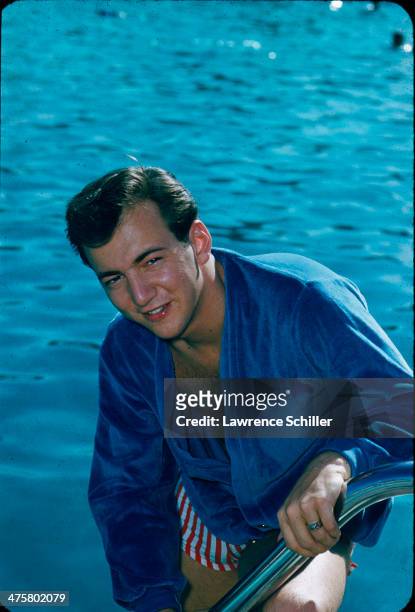 Portrait of American singer and actor Bobby Darin as he poses in a shirt and swim trunks on the steps of a swimming pool, Las Vegas, Nevada, 1959.