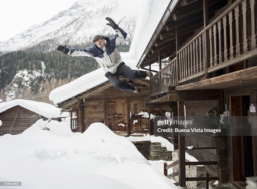 Young man diving in snow from balcony