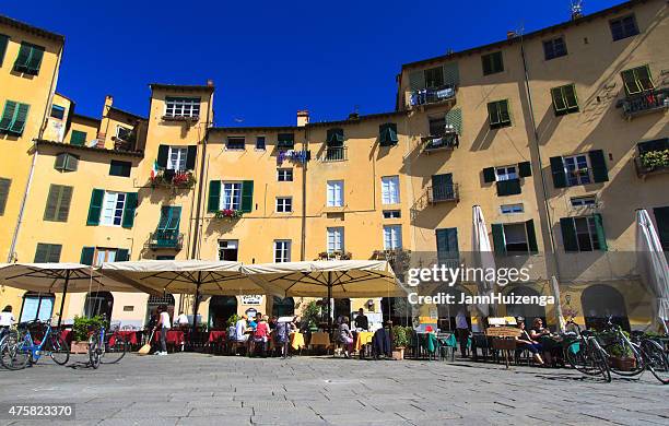 les clients sur les tables extérieures dans piazza dell''anfiteatro à lucques, italie - lucca photos et images de collection