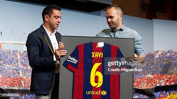 Xavi Hernandez is presented with a signed shirt by team-mate Andres Iniesta during the 'FC Barcelona Homage to Xavi' ahead of his final game for the...