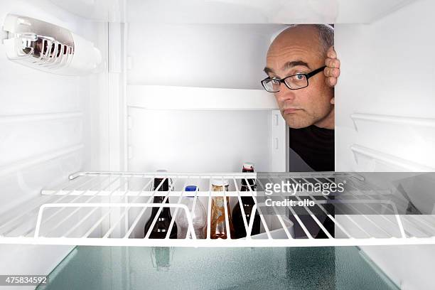 middle-aged man opens a fridge - refrigerator door stock pictures, royalty-free photos & images