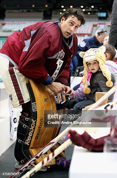 Roberto Luongo of the Vancouver Canucks helps his son, Gianni Luongo, with his skates before the family skate after practice for the 2014 Tim Hortons...