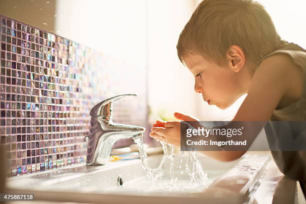 little boy drinking tap water - waterkraan stockfoto's en -beelden