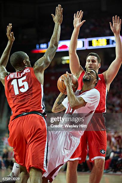 Rashad Madden of the Arkansas Razorbacks drives between Donte Williams and Nemanja Djurisic of the Georgia Bulldogs at Bud Walton Arena on March 1,...