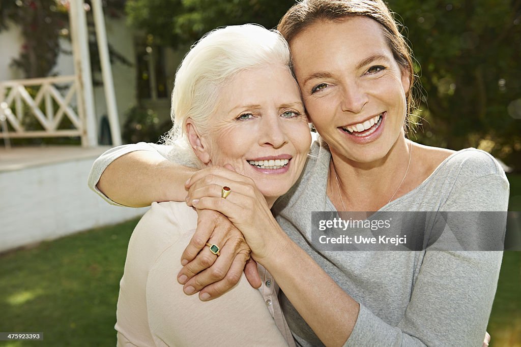 Senior woman and adult daughter embracing outdoors