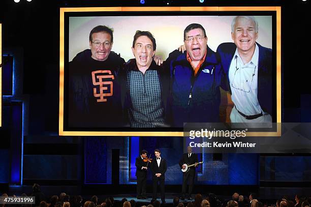 Photo of actors Robin Williams, Martin Short, Jerry Lewis and Steve Martin is displayed on a screen above actor Martin Short performing onstage...