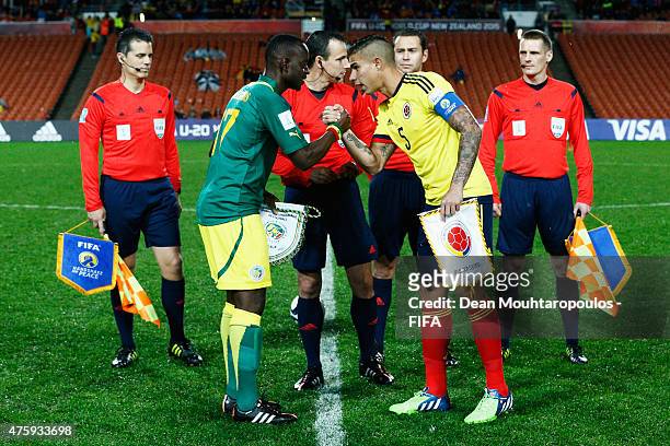 Captains, Roger Gomis of Senegal and Juan Sebastian Quintero of Colombia shake hands in front of the officials and the Handshake for Peace flags...