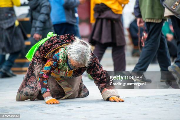 tibetan pilgrim prostrating at the barkhor in lhasa, tibet. - tibetan culture stock pictures, royalty-free photos & images