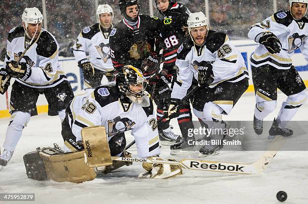 Goalie Marc-Andre Fleury of the Pittsburgh Penguins watches the puck as teammates Rob Scuderi, Joe Vitale, and Craig Adams skate behind, against...