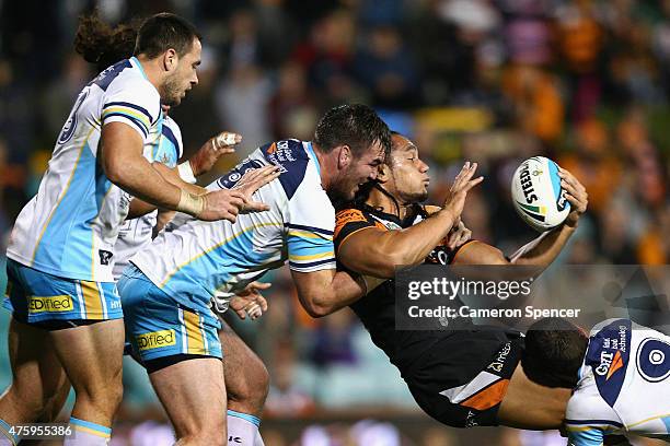 Martin Taupau of the Tigers offloads the ball in a tackle during the round 13 NRL match between the Wests Tigers and the Gold Coast Titans at...