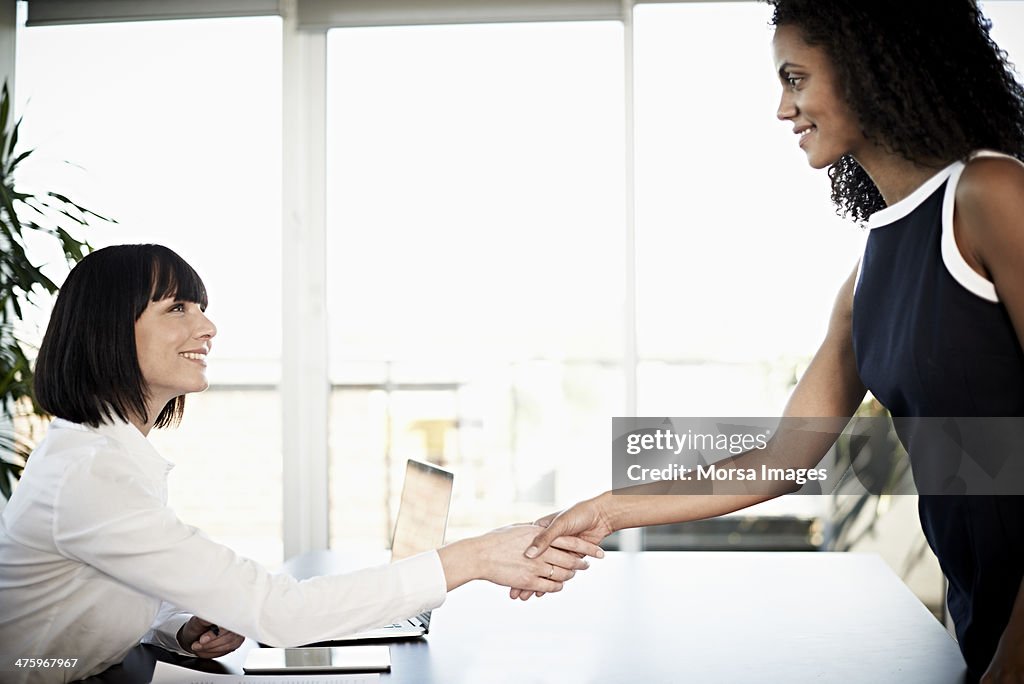 Businesswoman welcoming colleague to meeting