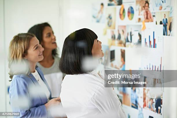 businesswomen looking at images on the wall - waist up photos stock-fotos und bilder