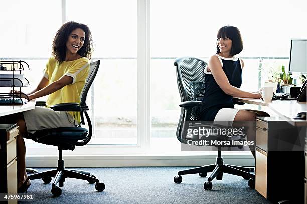 female coworkers laughing - office chair stock pictures, royalty-free photos & images