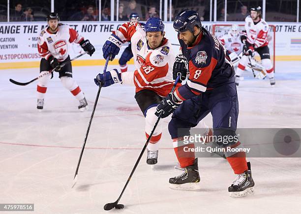 Nedeljko Lukacevic of the United States of America controls the puck infront of Frazer McLaren of Canada during the 2015 Ice Hockey Classic match...