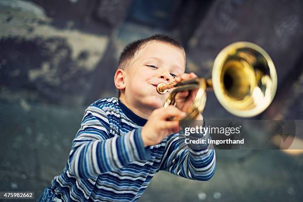 glücklich kleiner junge spielt trompete - music instrument stock-fotos und bilder