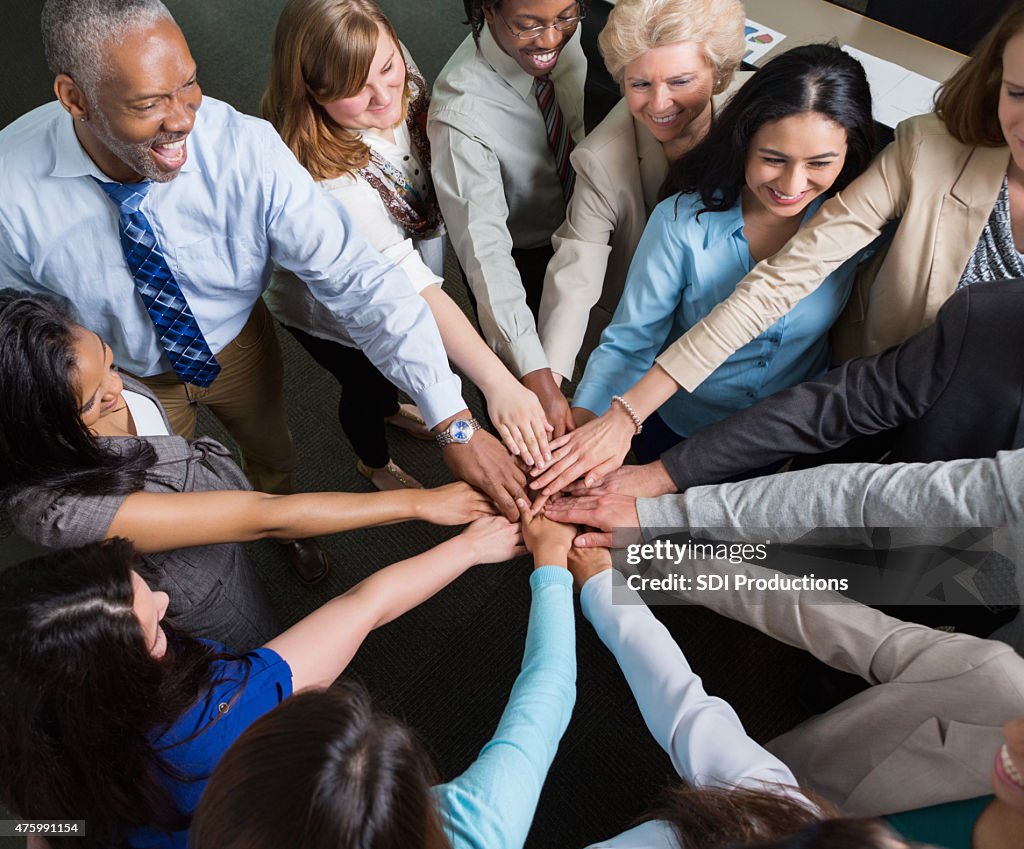 Diverse team of professionals with hands in teamwork huddle