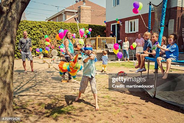 little girl hitting pinata at birthday party in suburb backyard. - kids party stock pictures, royalty-free photos & images