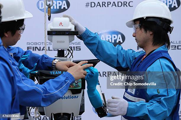 Members of Team Aero from the University of Tokyo prepare their robot in the 'Meet the Robots' area of th Defense Advanced Research Projects Agency...