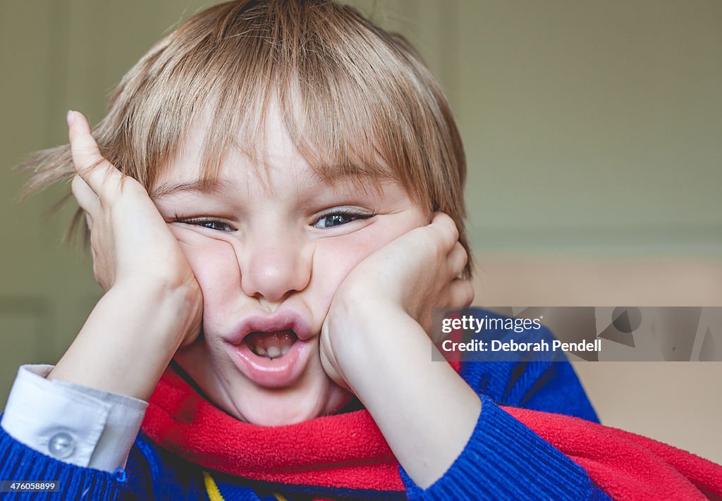 Young boy squashes his face between his hands
