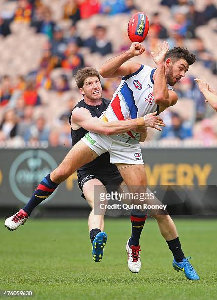 Taylor Walker of the Crows handballs whilst being tackled by Sam Rowe of the Blues during the round 10 AFL match between the Carlton Blues and the...