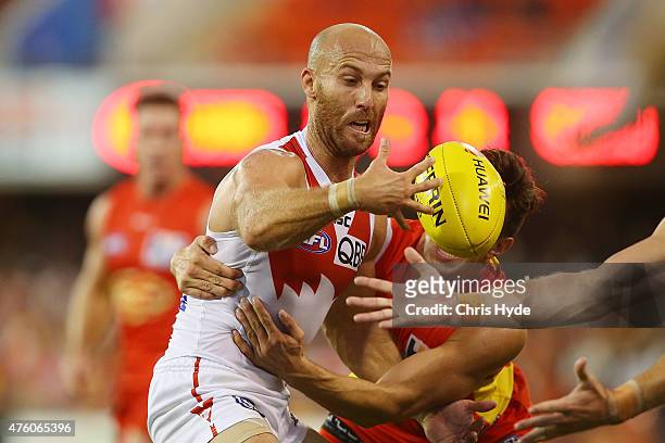 Jarrad McVeigh of the Swans is tackled during the round 10 AFL match between the Gold Coast Suns and the Sydney Swans at Metricon Stadium on June 6,...