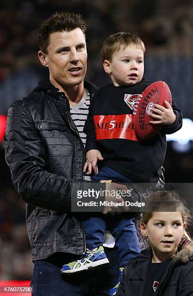 Fomer Bombers players Matthew Lloyd looks on with his kids as the players come out during the round 10 AFL match between the Essendon Bombers and the...