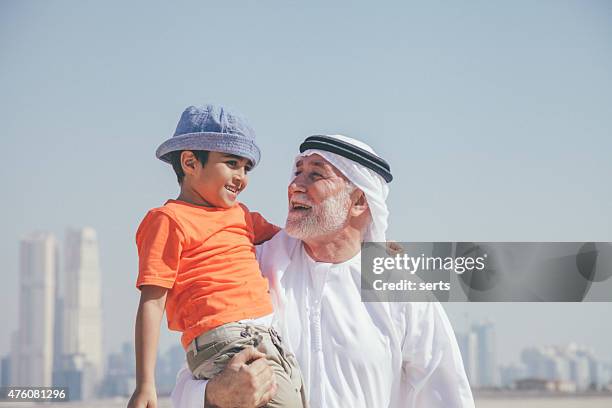 arabische großvater und kleine jungen, die spaß am strand - arabische familie stock-fotos und bilder