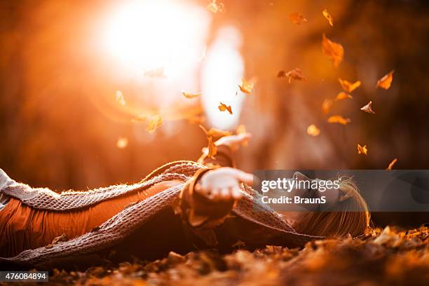 carefree woman relaxing and throwing autumn leaves in nature. - throwing leaves stock pictures, royalty-free photos & images