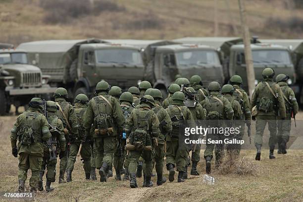 Soldiers who were among several hundred that took up positions around a Ukrainian military base walk towards their parked vehicles in Crimea on March...