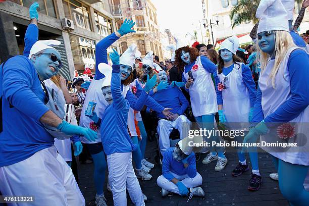 Revellers dressed as 'Smurfs' enjoy the carnival whilst a child sits and waits to go to the fair during the Santa Cruz de Tenerife Carnival on March...