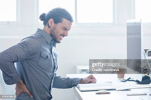 young business man with holding his back in pain. - lower back stock pictures, royalty-free photos & images
