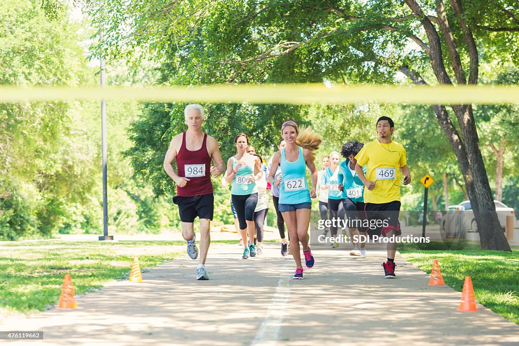 Diverse runners racing excitedly toward finish line during marathon