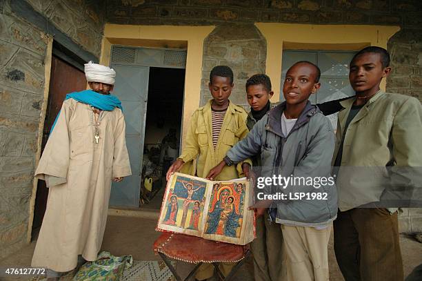 ethiopian kids and priest showing old bible. - ethiopian ethnicity stock pictures, royalty-free photos & images