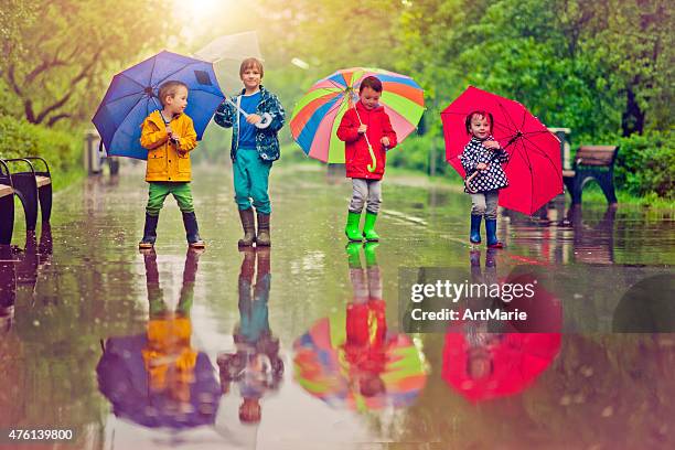 chilren under umbrella - standing in the rain girl stockfoto's en -beelden