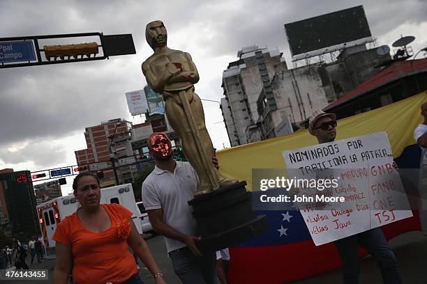 Protester carries a giant Oscar statue during an anti-government demonstration on March 2, 2014 in Caracas, Venezuela. Venezuela has one of the...