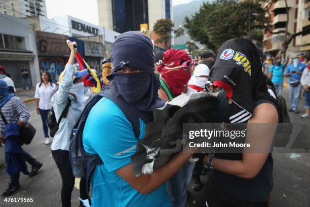 Protesters carry rocks to throw at national guard troops following an anti-government demonstration on March 2, 2014 in Caracas, Venezuela. Venezuela...