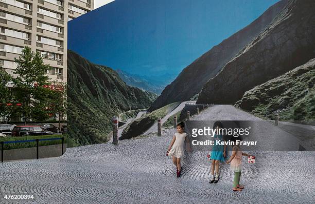 Chinese girls stand in front of a large photograph of the Swiss Alps during a tourism event sponsored by the Swiss government on June 6, 2015 in a...