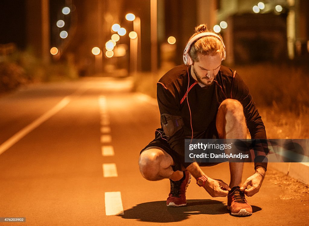 Man tying shoe laces and taking a break from jogging