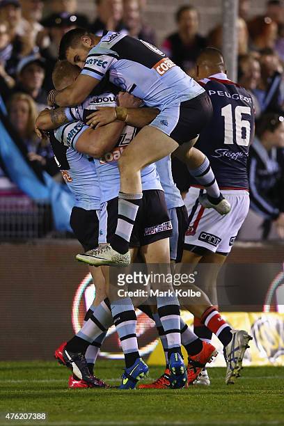 Jack Bird of the Sharks jumps on his team mates as they celebrate with Luke Lewis of the Sharks after he scored a try during the round 13 NRL match...
