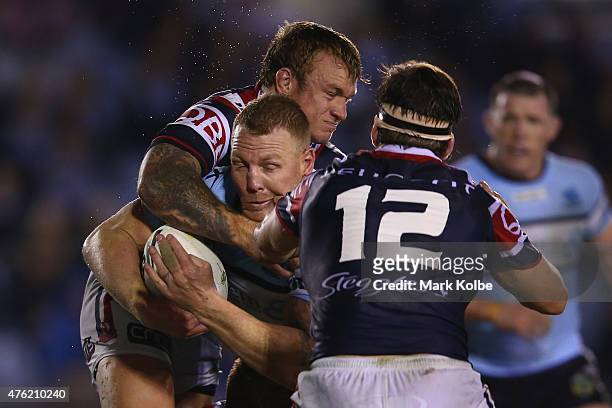 Jake Friend and Aiden Guerra of the Roosters tackle Luke Lewis of the Sharks during the round 13 NRL match between the Sharks and the Roosters at...