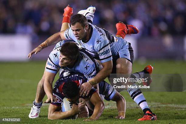 Roger Tuivasa-Sheck of the Roosters is tackled by Blake Ayshford and Wade Graham of the Sharks during the round 13 NRL match between the Sharks and...