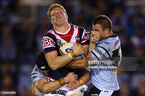 Dylan Napa of the Roosters is tackled by Michael Ennis and Wade Graham of the Sharks during the round 13 NRL match between the Sharks and the...