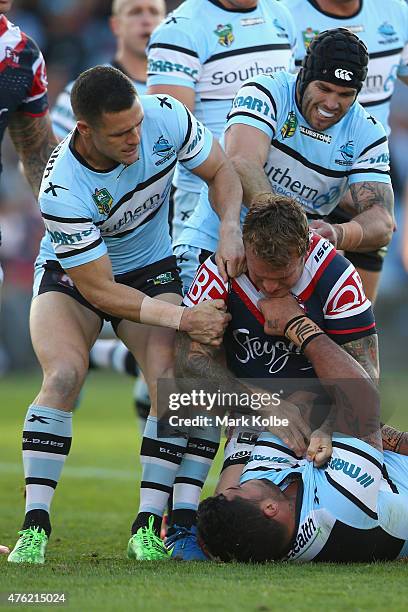 Michael Gordon and Michael Ennis of the Sharks pull away Jake Friend of the Roosters as he scuffles with Andrew Fifita of the Sharks during the round...