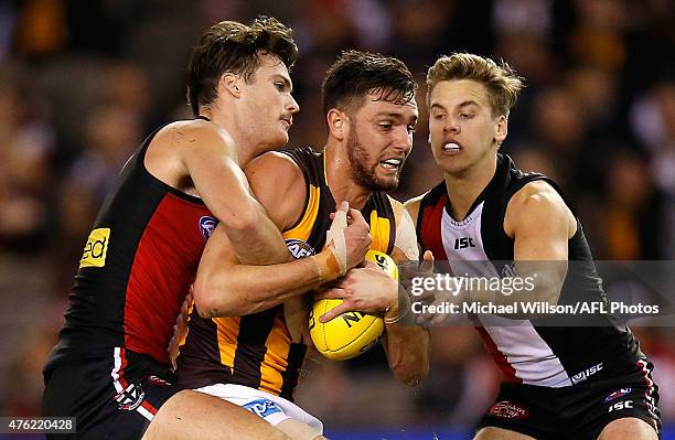 Jack Gunston of the Hawks is tackled by Dylan Roberton and Jack Lonie of the Saints during the 2015 AFL round ten match between the St Kilda Saints...