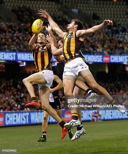 Isaac Smith of the Hawks, Adam Schneider of the Saints and Ben Stratton of the Hawks compete for the ball during the 2015 AFL round ten match between...
