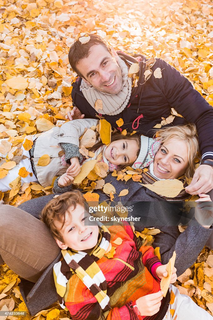 Joyeuse famille allongé en amas de feuilles en automne.