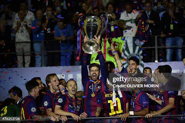 Barcelona's defender Gerard Pique raises the trophy next to Barcelona's Croatian midfielder Ivan Rakitic and Barcelona's midfielder Andres Iniesta...