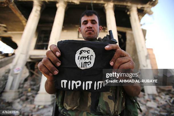 An Iraqi Shiite fighter from the Popular Mobilization units holds an Islamic State group patch as he inspects a council building in the city of...