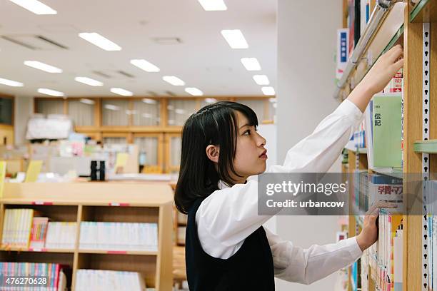 japanese high school, library. choosing a book, female student - reaching higher stock pictures, royalty-free photos & images