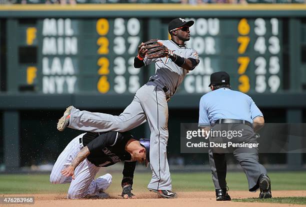 Shortstop Adeiny Hechavarria of the Miami Marlins turns a double play on Brandon Barnes of the Colorado Rockies on a bunt attempt by Kyle Kendrick of...